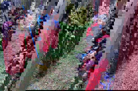 en gruppe barn som sitter på bakken utenfor en bygning