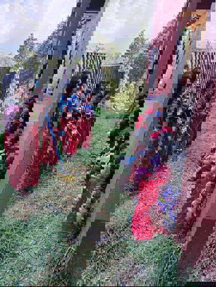 en gruppe barn som sitter på bakken utenfor en bygning