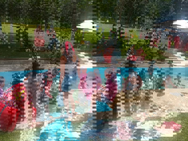 en gruppe mennesker som sitter på bakken ved et basseng